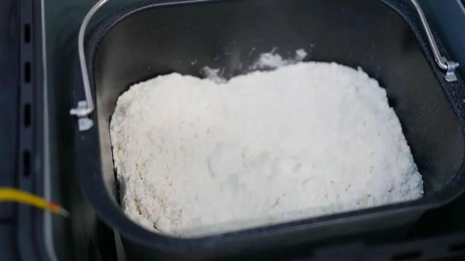 Batedor misturando farinha e ingredientes na cuba da panificadora