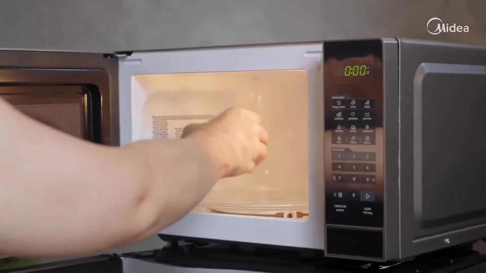 Xícara sendo colocada no prato giratório do micro-ondas Midea