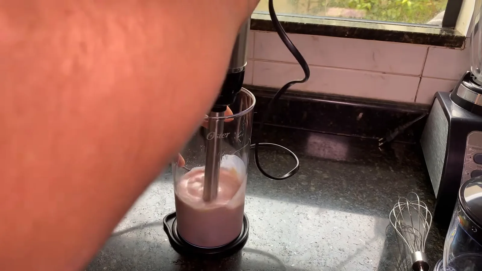 Mixer Oster triturando morangos congelados e iogurte no copo graduado