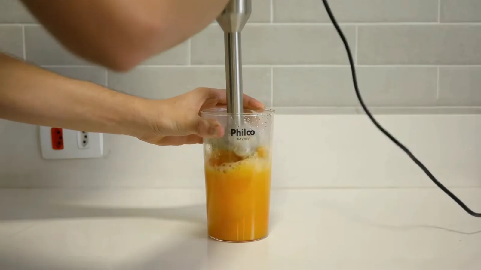 Mixer Philco batendo creme alaranjado no copo dosador alto