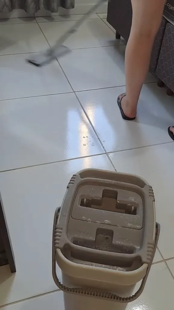 Mop sendo umedecido no balde e passando no piso