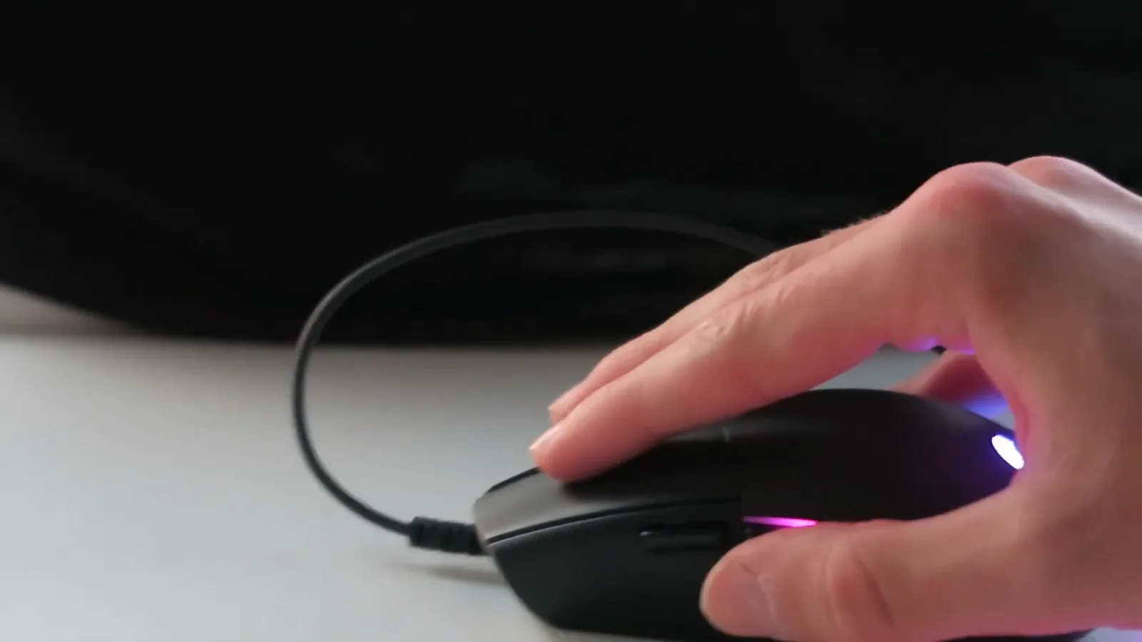 Usuário segurando o mouse gamer com iluminação RGB ativa