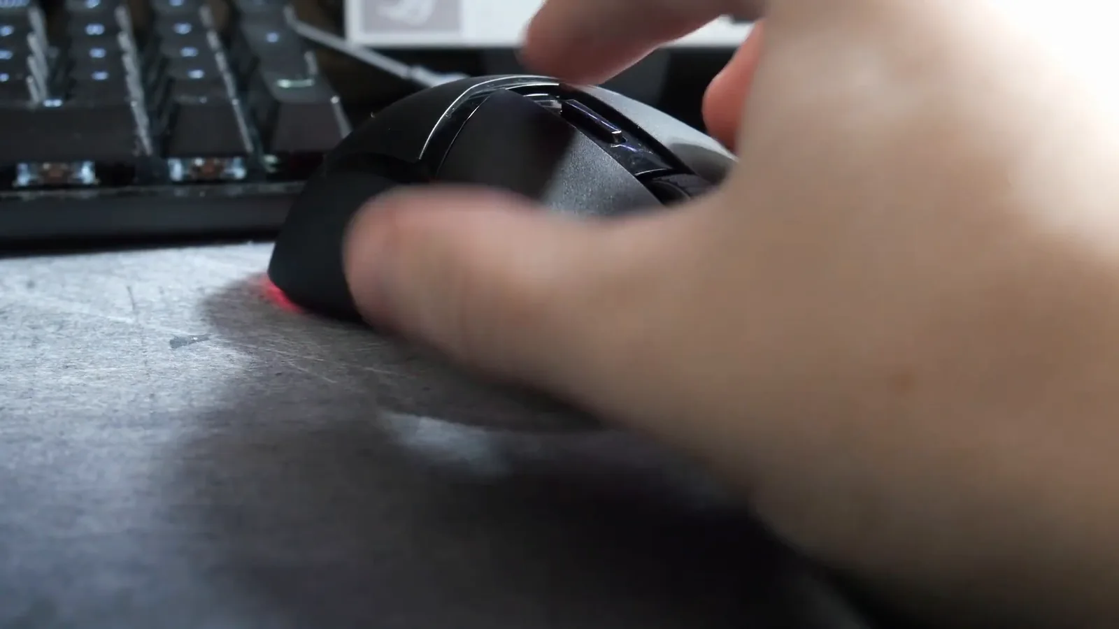 Mouse gamer com fio sendo manuseado sobre a mesa de jogos