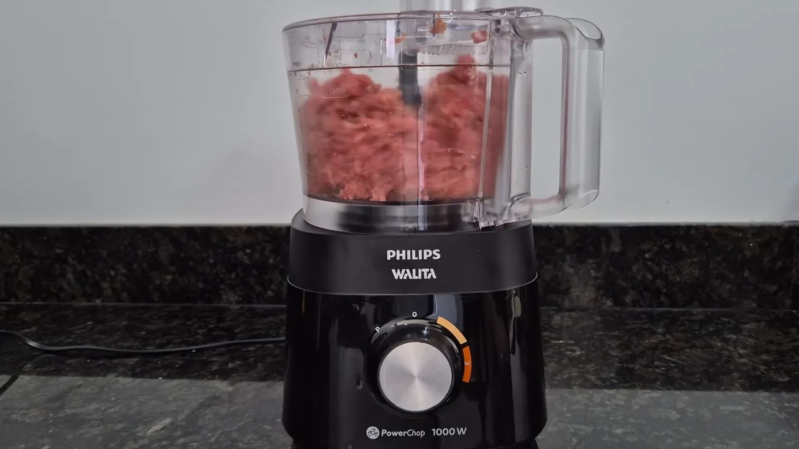 Multiprocessador moendo carne crua com a lâmina de corte na jarra