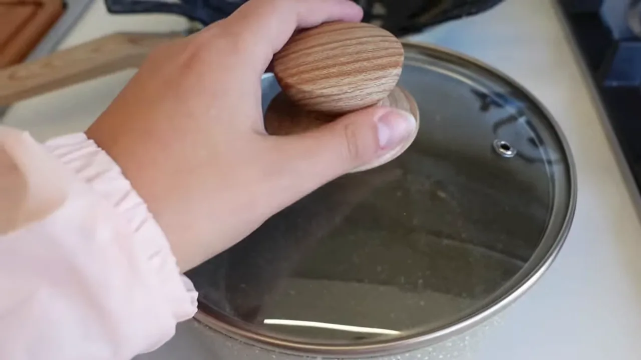 Panela Oster com tampa sendo manuseada na bancada da cozinha