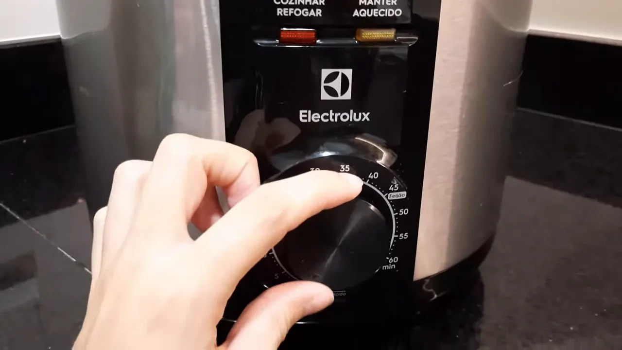 Usuária girando o botão do timer mecânico da panela de pressão