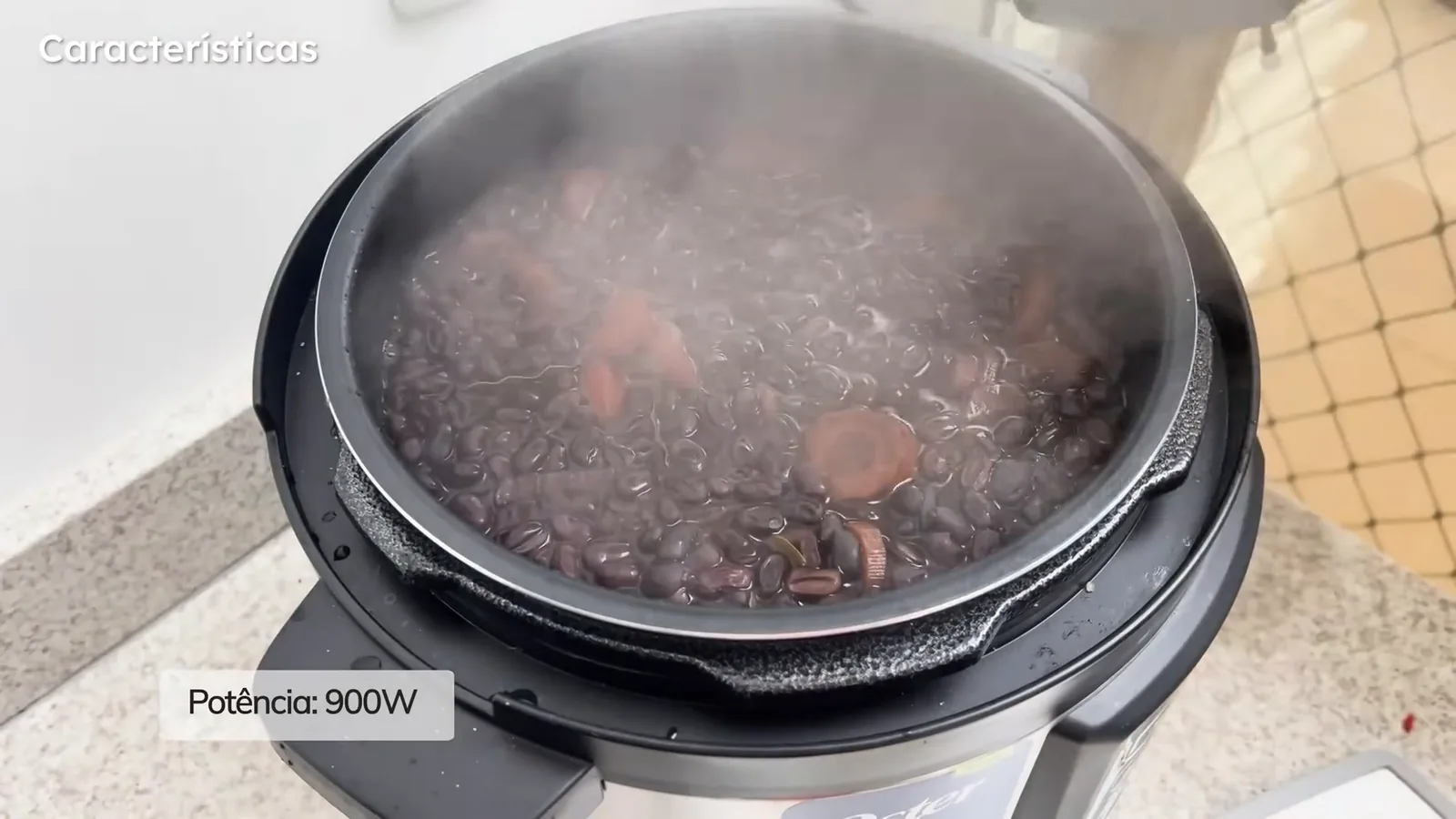 Panela de pressão Oster com feijoada quente fumegando em seu interior