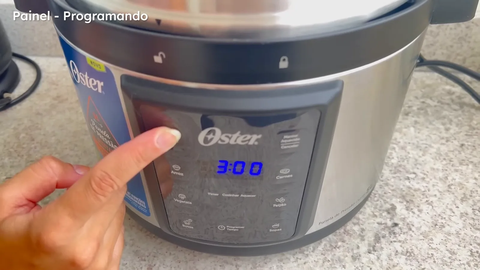 Painel digital da panela elétrica Oster sendo ajustado para o cozimento
