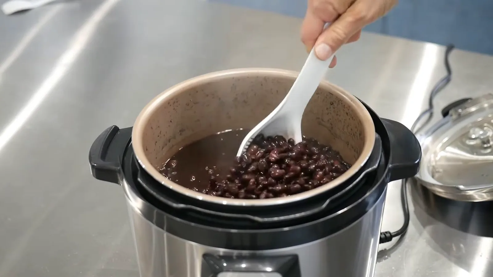 Panela de pressão elétrica preparando feijão preto com a concha plástica