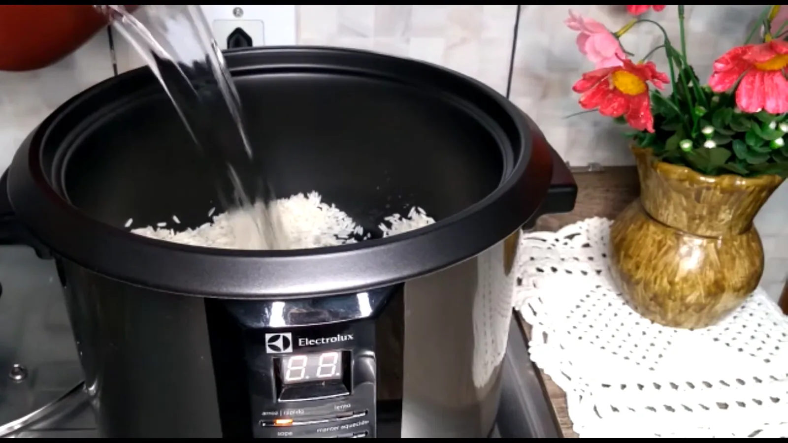 Adicionando água ao arroz dentro da panela elétrica Electrolux