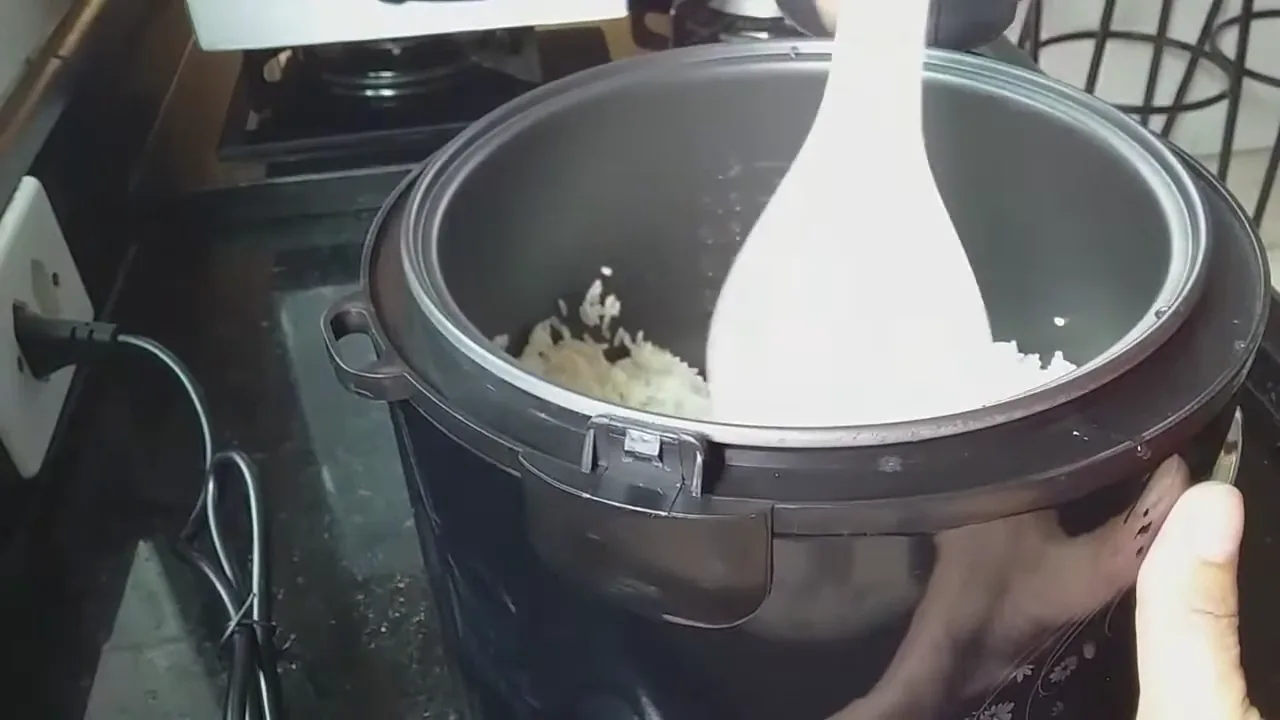 Misturando arroz e temperos na cuba da panela elétrica