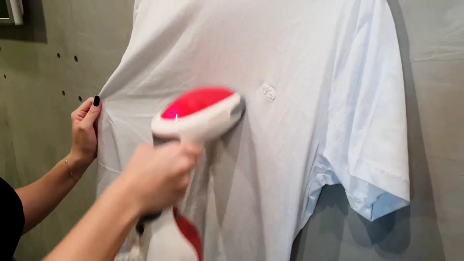 Vaporizador portátil desamassando camiseta branca pendurada no cabide