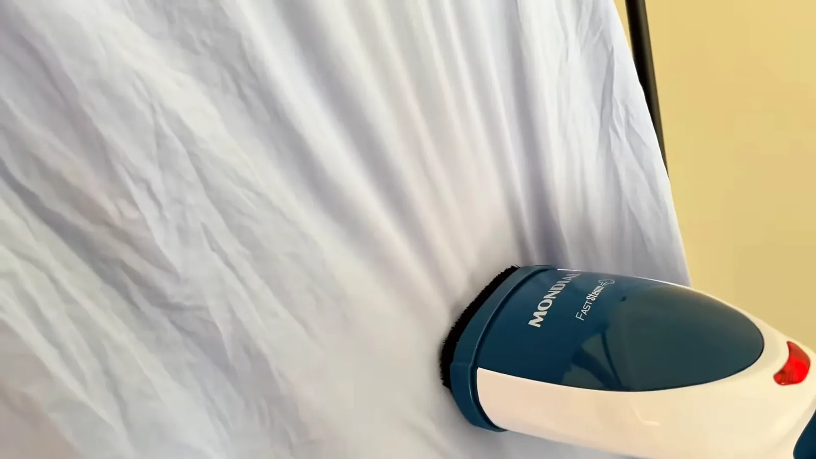 Passadeira a vapor Mondial VP-09 desamassando camisa azul pendurada no cabide