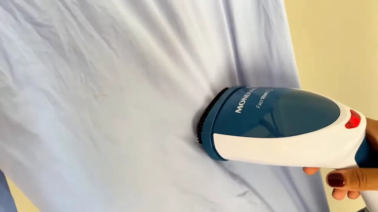 Passadeira a vapor portátil Mondial desamassando camisa azul no cabide