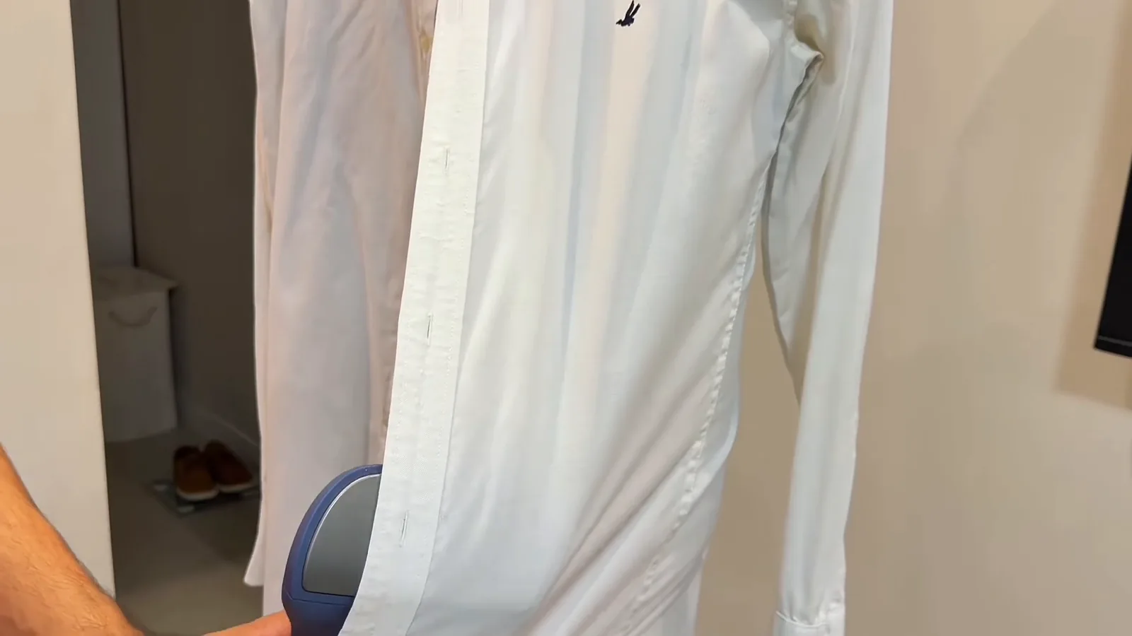 Passadeira a vapor desamassando a costura lateral da camisa branca
