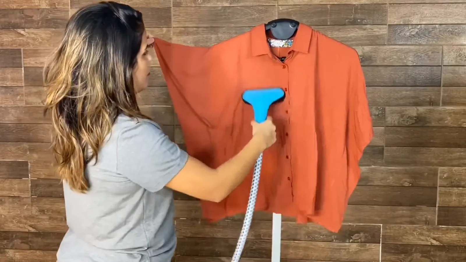 Bocal da passadeira a vapor alisando camisa pendurada no suporte