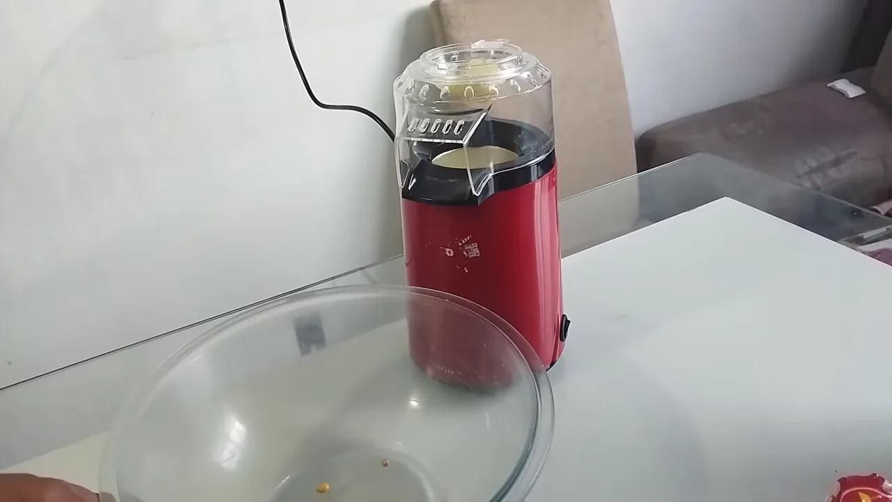 Pipoqueira elétrica funcionando e arremessando pipocas prontas na tigela