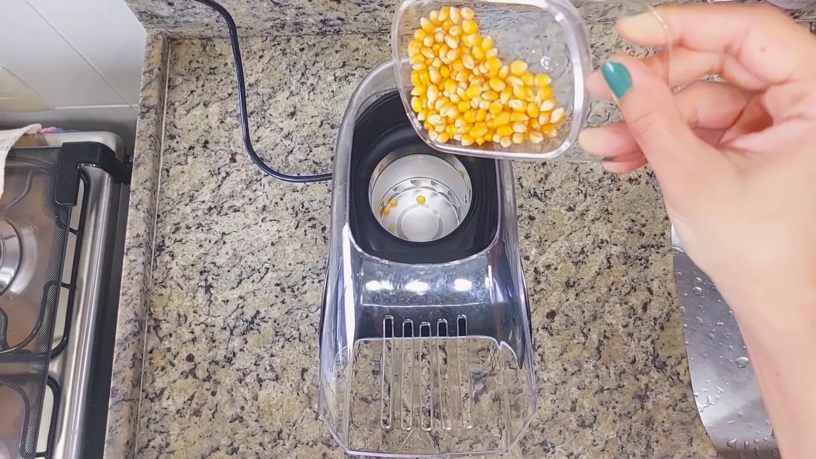 Milho sendo colocado no compartimento da pipoqueira elétrica Pop Time