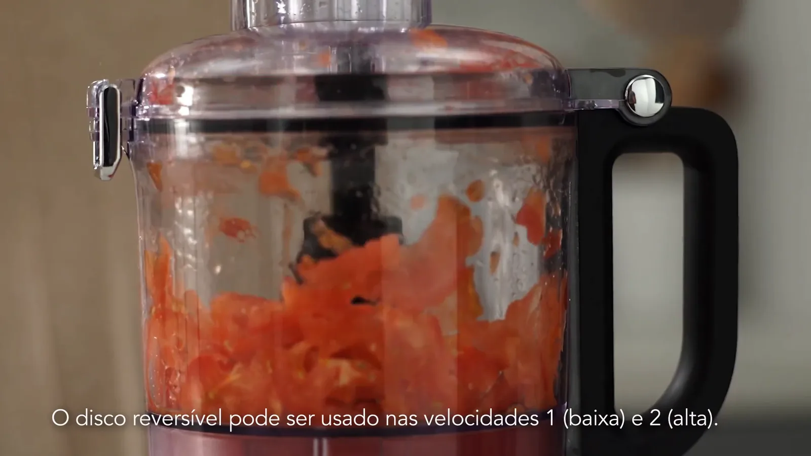 Processador de alimentos KitchenAid fatiando tomates com disco reversível em funcionamento