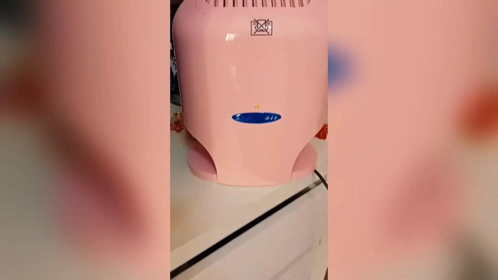 Purificador térmico Sterilair rosa ligado sobre cômoda no quarto