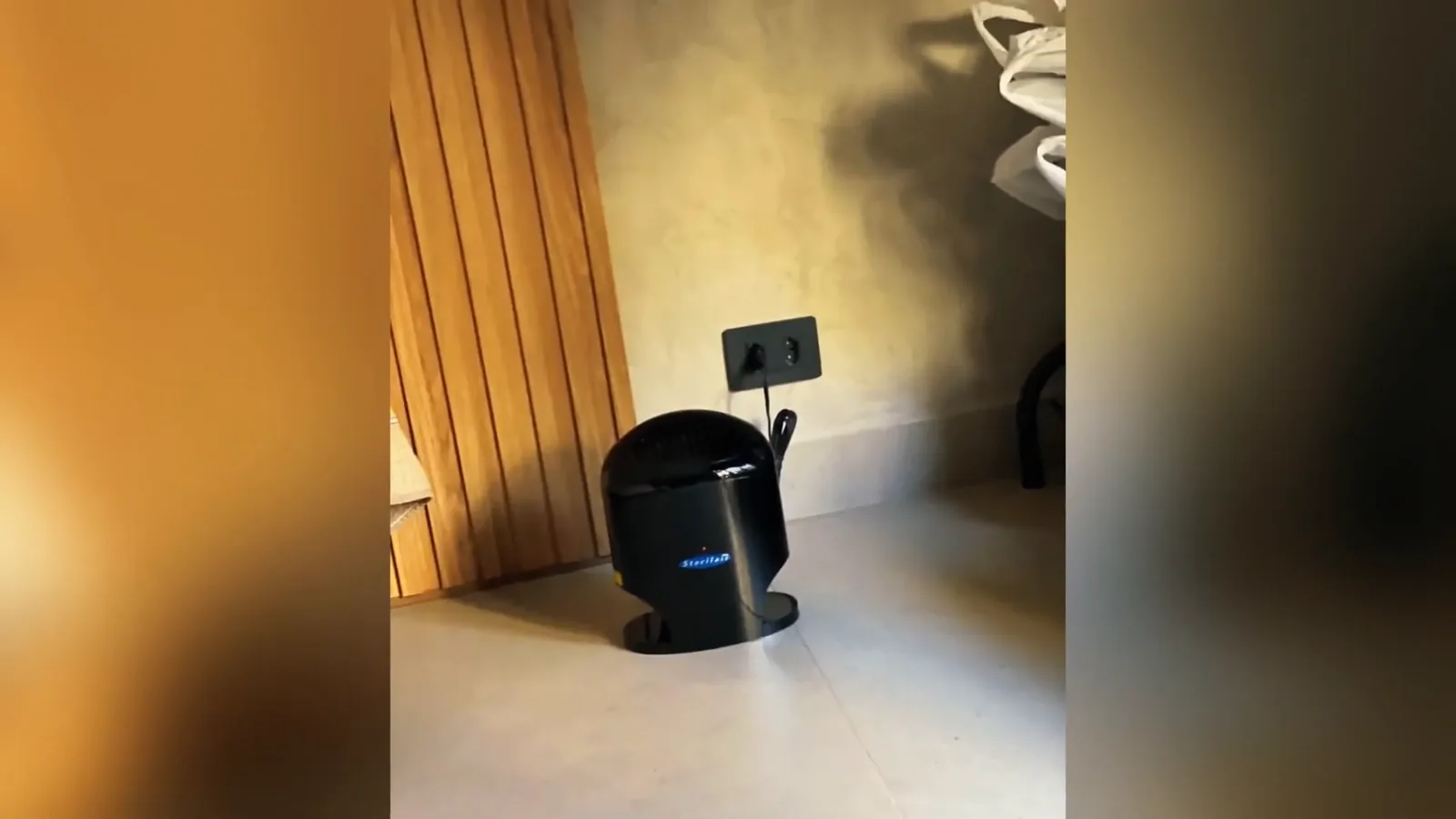 Esterilizador de ar Sterilair preto conectado na tomada no chão