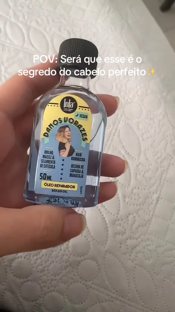 Frasco de 50 ml do óleo reparador Danos Vorazes segurado na mão