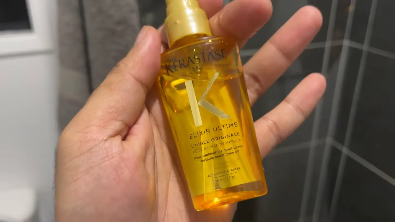Frasco do óleo capilar Kérastase Elixir Ultime segurado na mão