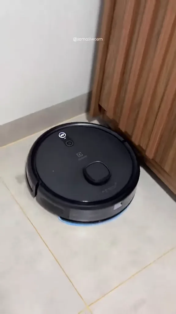 Robô aspirador realizando limpeza automática no chão ao contornar móvel