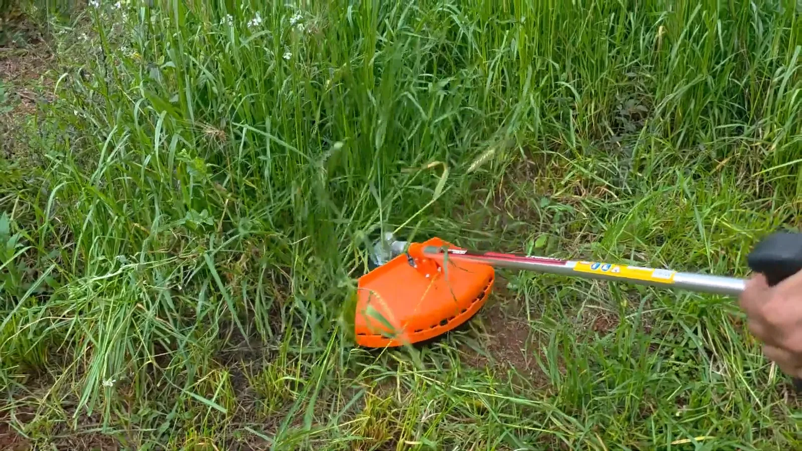 Roçadeira cortando vegetação densa com lâmina de três pontas