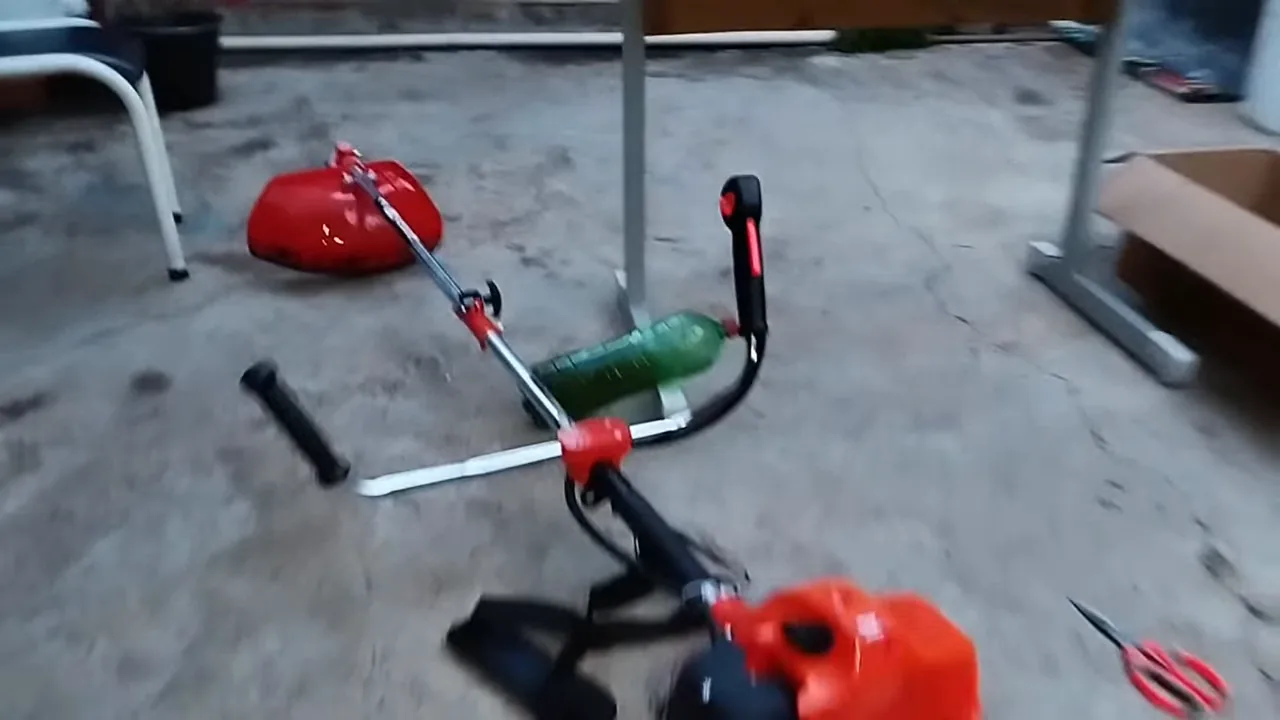 Roçadeira a gasolina Nakasaki ligada e vibrando no piso