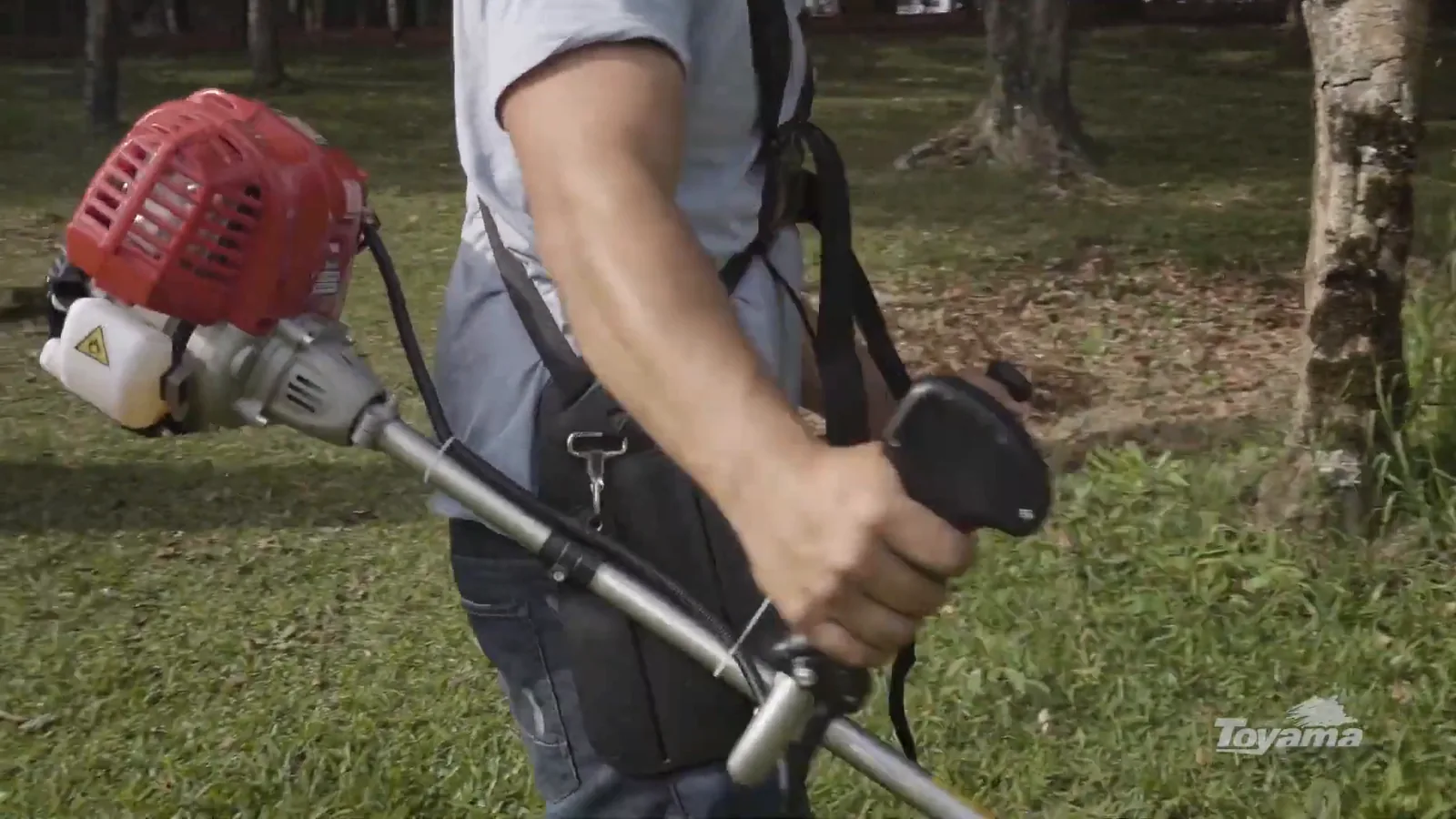 Operador manuseando a roçadeira pelo guidão ergonômico durante o corte
