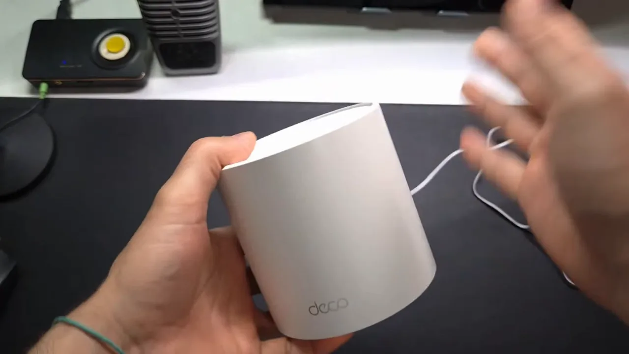 Roteador mesh Deco X50 ligado sendo manuseado com luz de status ativa