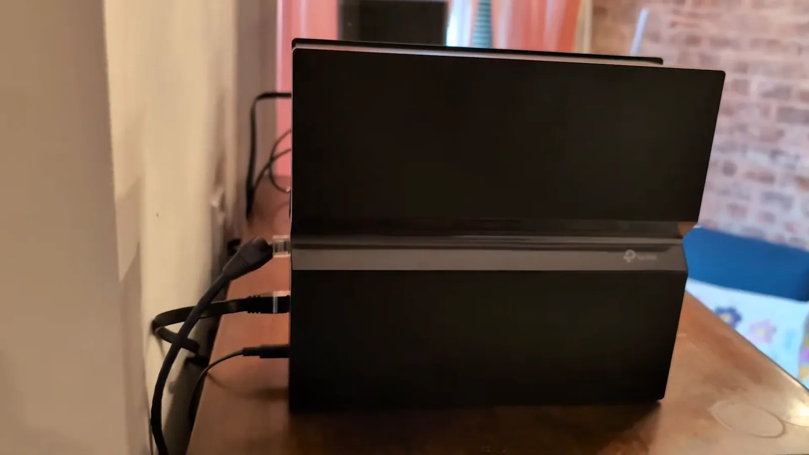 Roteador Archer BE550 com cabos conectados em funcionamento sobre o móvel