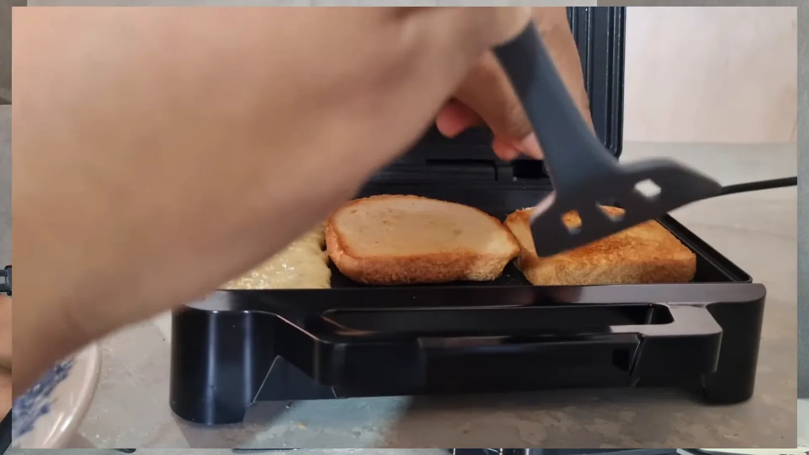 Pão e queijo dourando na chapa antiaderente funda da sanduicheira