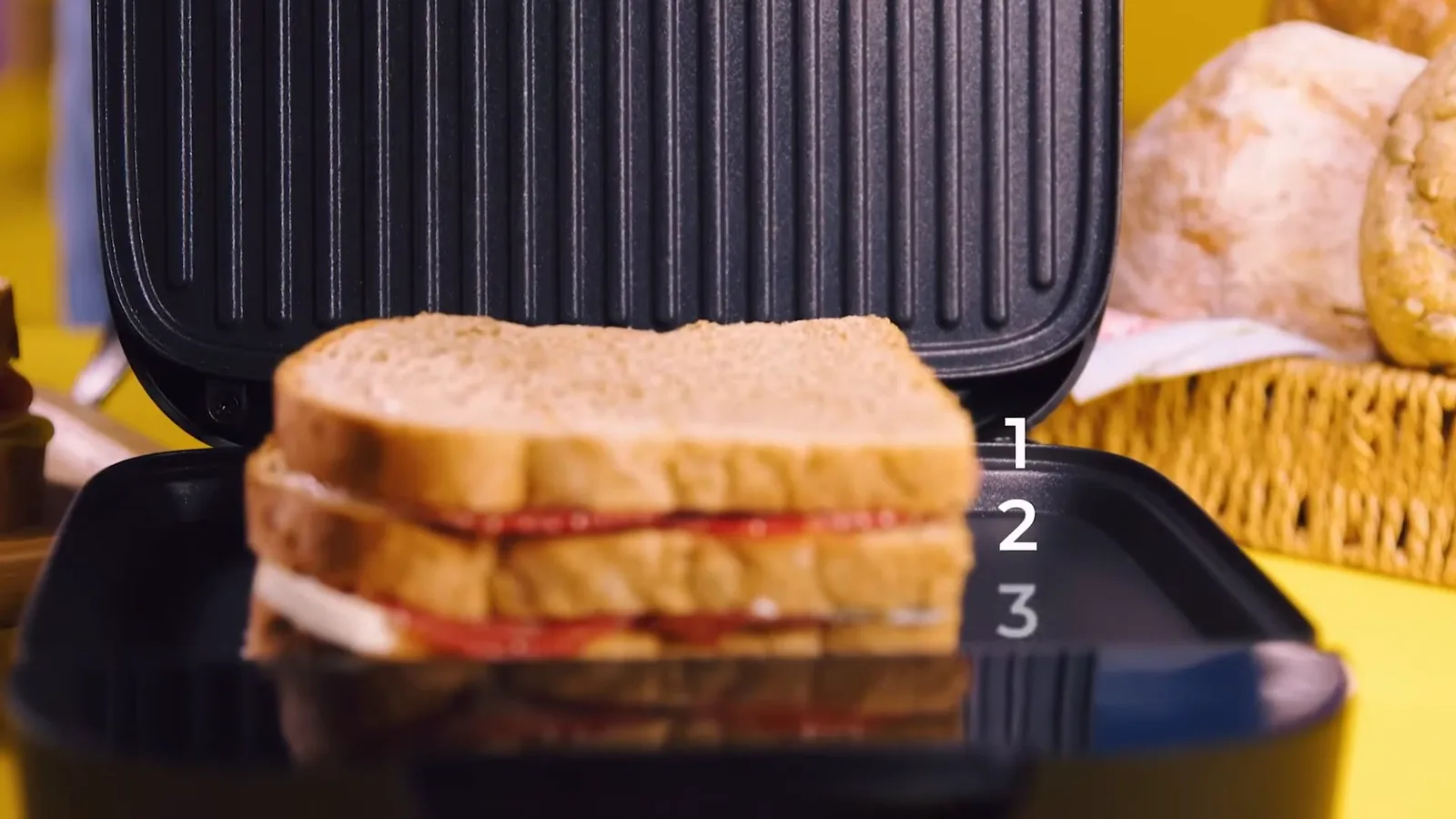 Sanduicheira com chapa espaçosa recebendo sanduíche com recheio alto