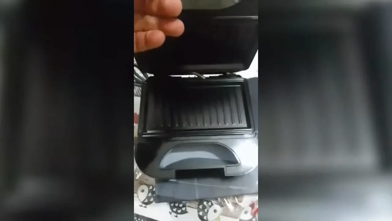 Abertura e fechamento da tampa da sanduicheira mostrando as chapas internas