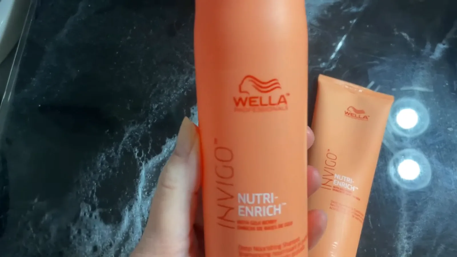 Frasco de shampoo Wella Invigo Nutri-Enrich exibido em mãos