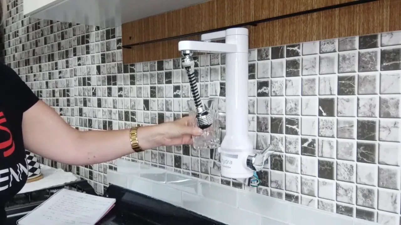 Saída de água purificada enchendo um copo de vidro