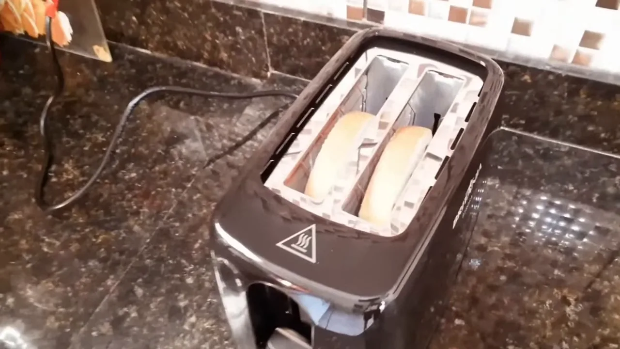 Acionamento da torradeira elétrica com fatias de pão no compartimento