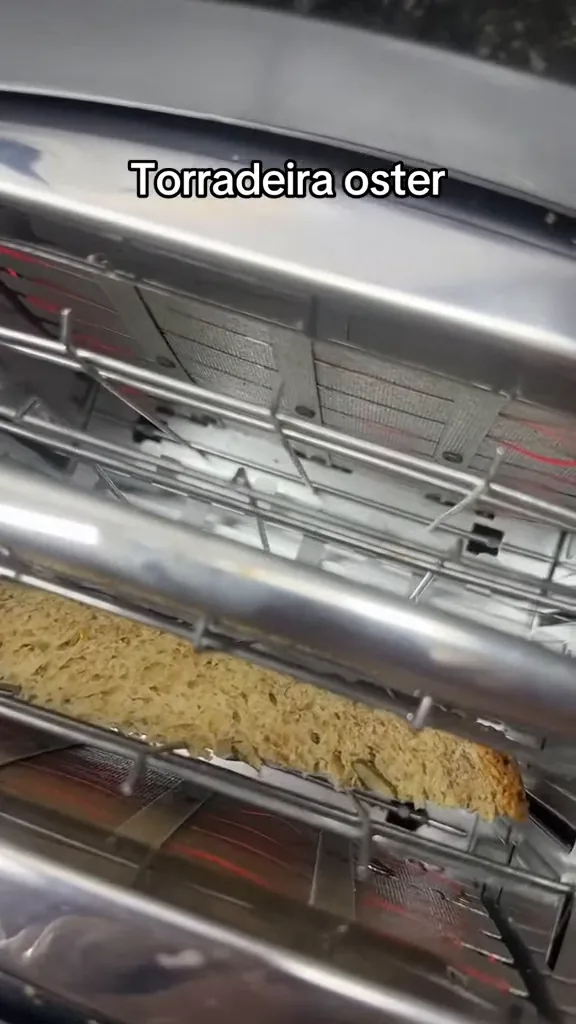 Resistências internas aquecidas tostando fatia de pão na torradeira Oster