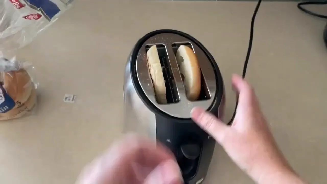Pão bagel colocado nas fendas da torradeira Oster para tostar