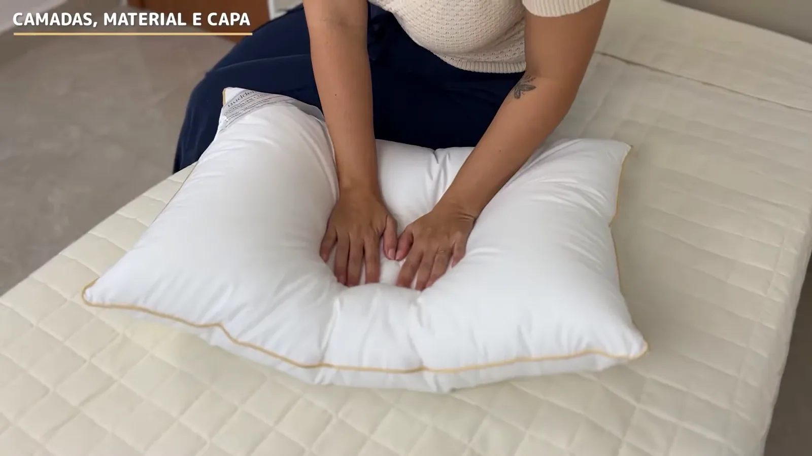 Mãos pressionando o travesseiro macio de microfibra sobre a cama