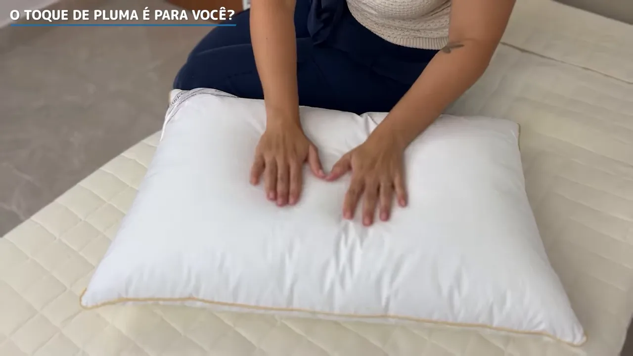 Mãos pressionando o travesseiro para demonstrar a maciez e afundamento