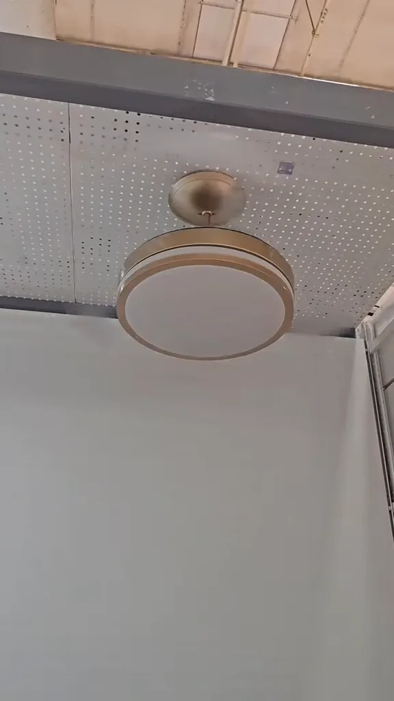 Ventilador de teto com pás abertas funcionando sobre suporte metálico