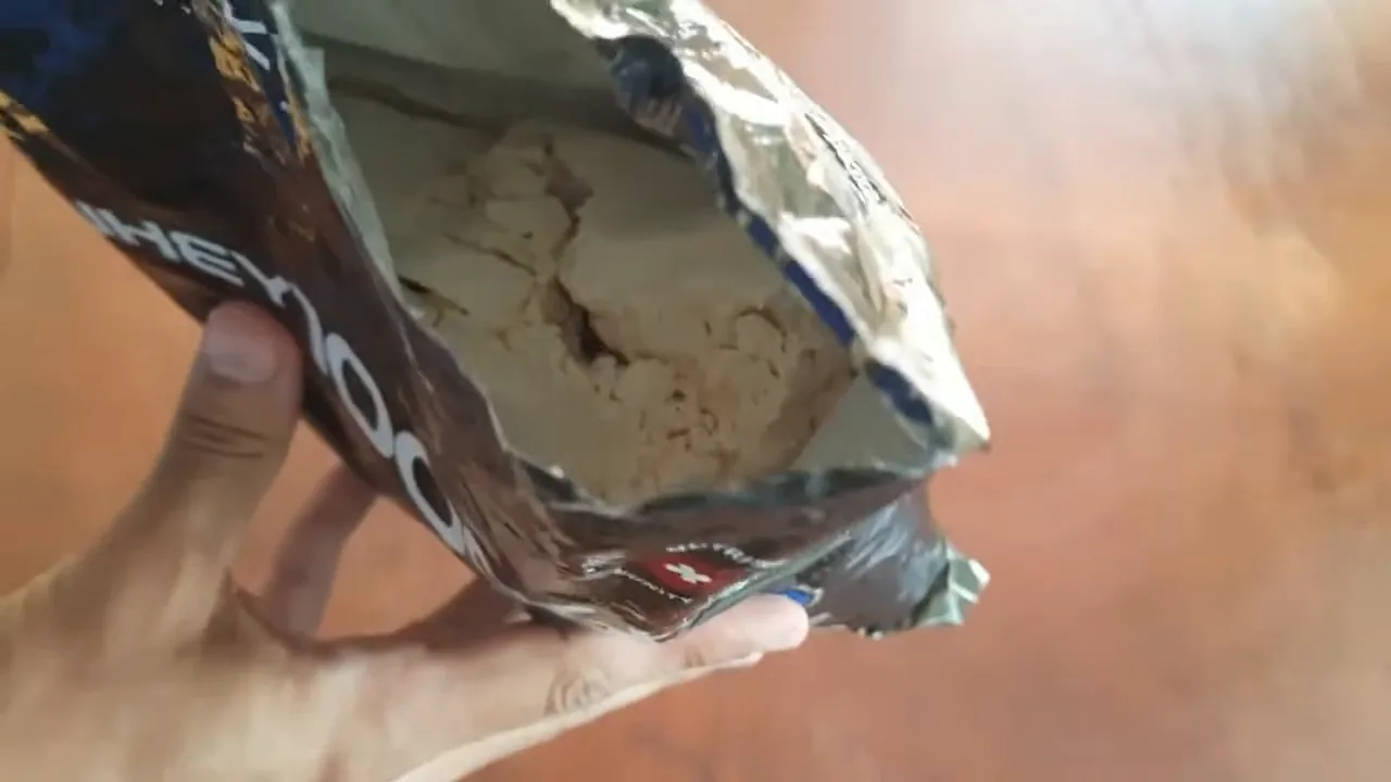 Abertura do pacote refil revelando o pó de whey protein