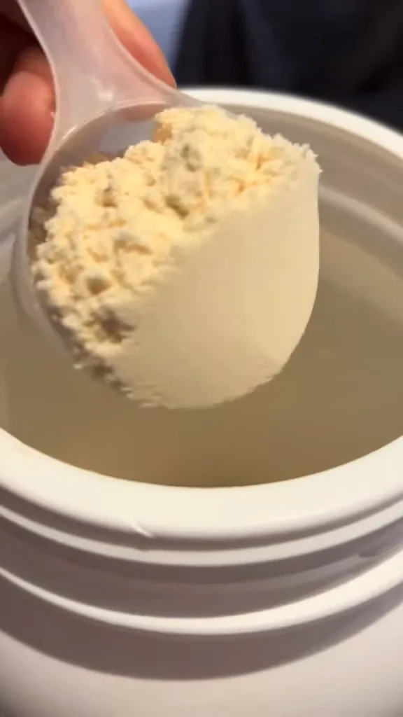 Scoop dosador exibindo o pó do whey Tasty Iso no pote