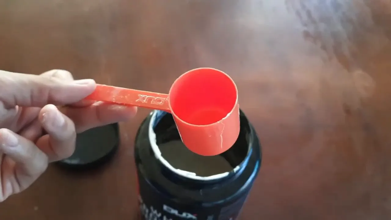 Dosador scoop laranja sobre o pote aberto do whey protein concentrado