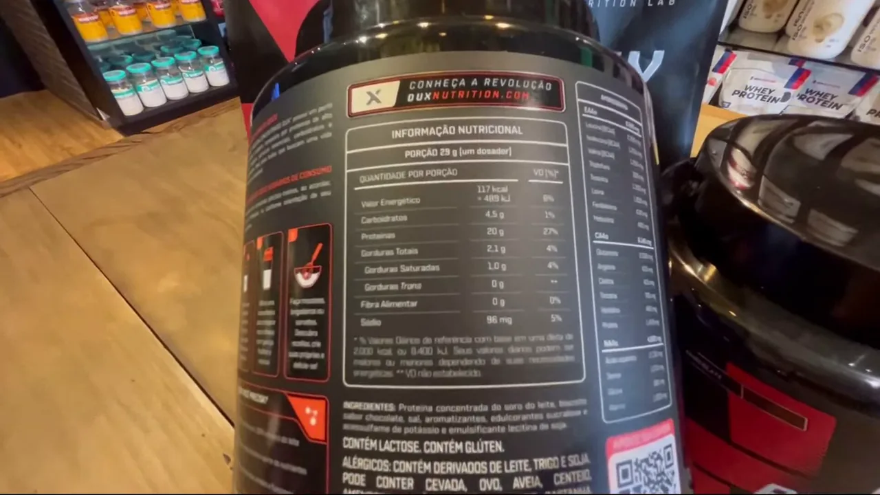 Manuseio do pote de whey concentrado exibindo as informações nutricionais