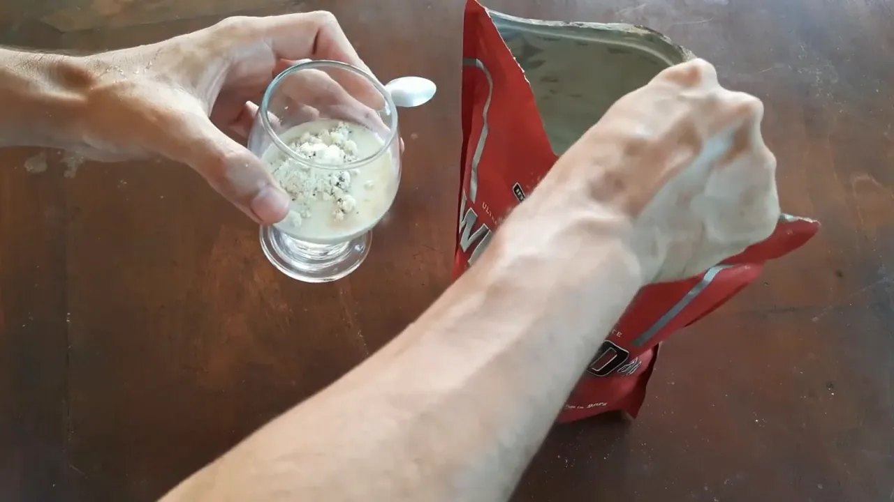 Colher retirando porção de whey protein da embalagem para preparo
