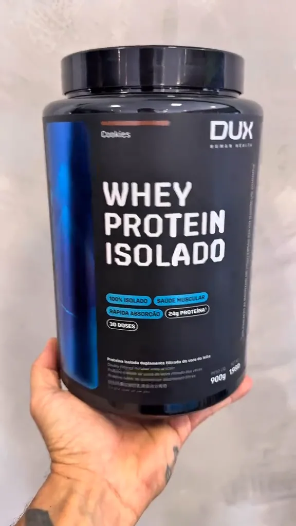 Pote de whey protein isolado Dux Nutrition exibido na mão